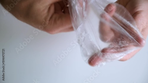 A round plate bag. Men's hands open a new disposable cellophane bag. Rustling sounds. Small plastic pack. Medical cap for hair. Grocery package. High quality 4K footage.