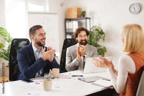 Team members gather in a bright office to collaborate and share ideas. They express enthusiasm and support for one another's contributions to the discussion.