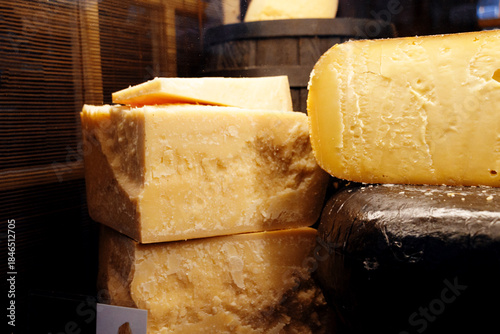 Close up of aged cheese wheels and thick slices in a gourmet shop. Natural texture and rich color highlight artisanal dairy products for food marketing, delicatessen branding.