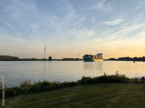 Containerschiff auf ruhigem Fluss bei Sonnenuntergang