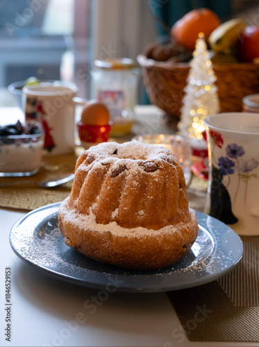 A plate Klougl with flowers, with Christmas holidays decoration atmosphere and festive ambiance. It's a cake traditionally baked in a distinctive ring pan.