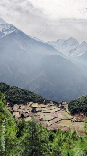 Himalayas region, settlement in a mountain valley, majestic views of the snowy mountains peaks, vertical nature background of a Himalayan mountain range, green valley under the mountains.