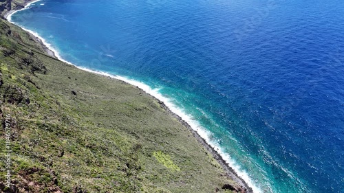 Aerial 4K drone footage of dramatic coastal cliffs and lighthouse viewpoint on Madeira island, overlooking the deep blue Atlantic Ocean and rugged shoreline in clear daylight.