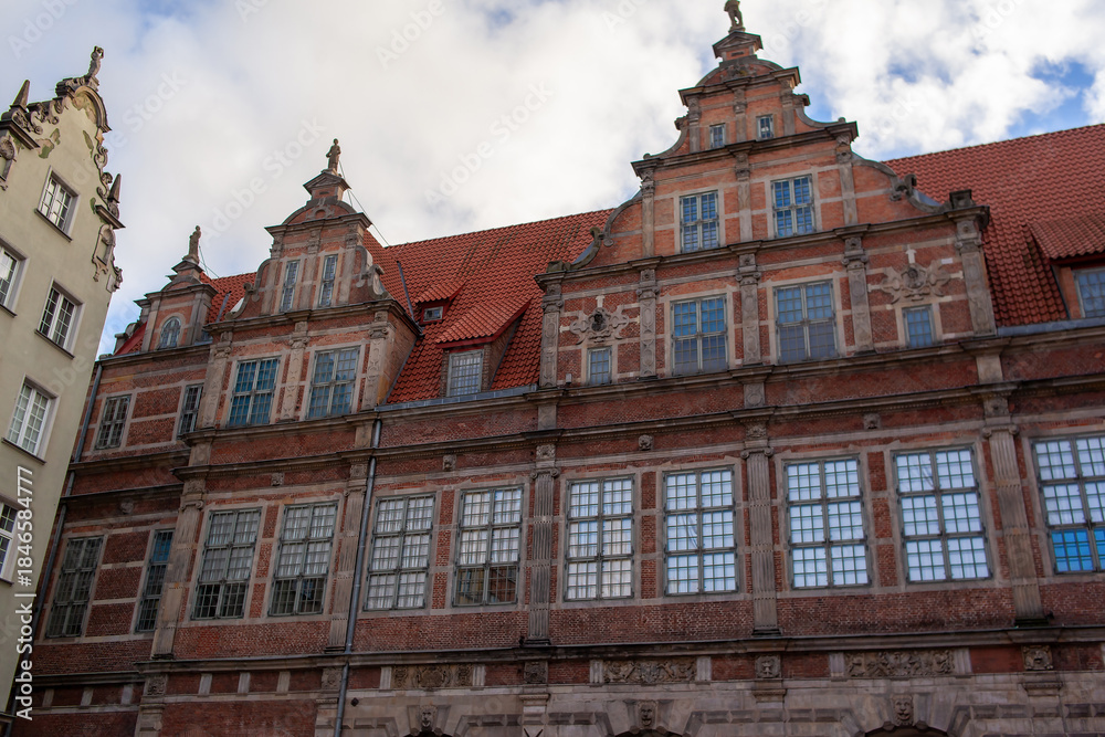 Fototapeta premium A historic brick building in Gdansk, Poland. The structure features multiple large windows and decorative elements on its facade. Grand entrance of Gdansk Green Gate