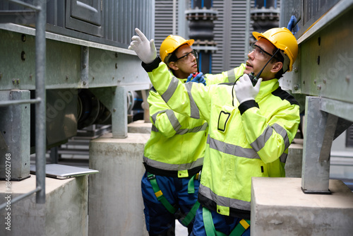 Photos Engineers talk on a walkie talkie and inspecting machinery, wearing hard hats an