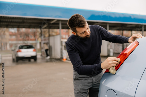 Car care concept with man cleaning vehicle windshield