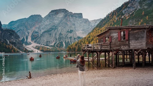 Scenic view of wooden boathouse on Lago di Braies with tourists in various activities at Dolomites, Italy