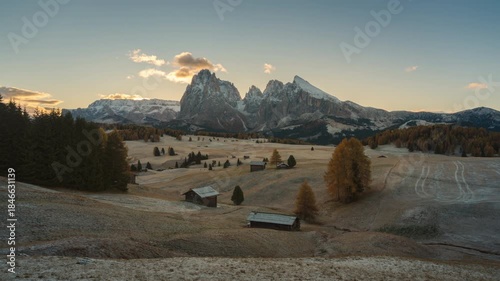 Alpine landscape of sunrise over Alpe di Siusi with wooden huts and autumn grass hill in Dolomites, Italy