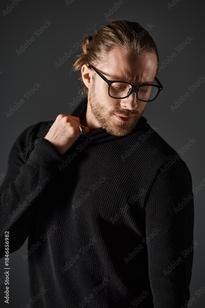 Obraz premium Stylish man in black attire showcasing elegance in a grey studio setting