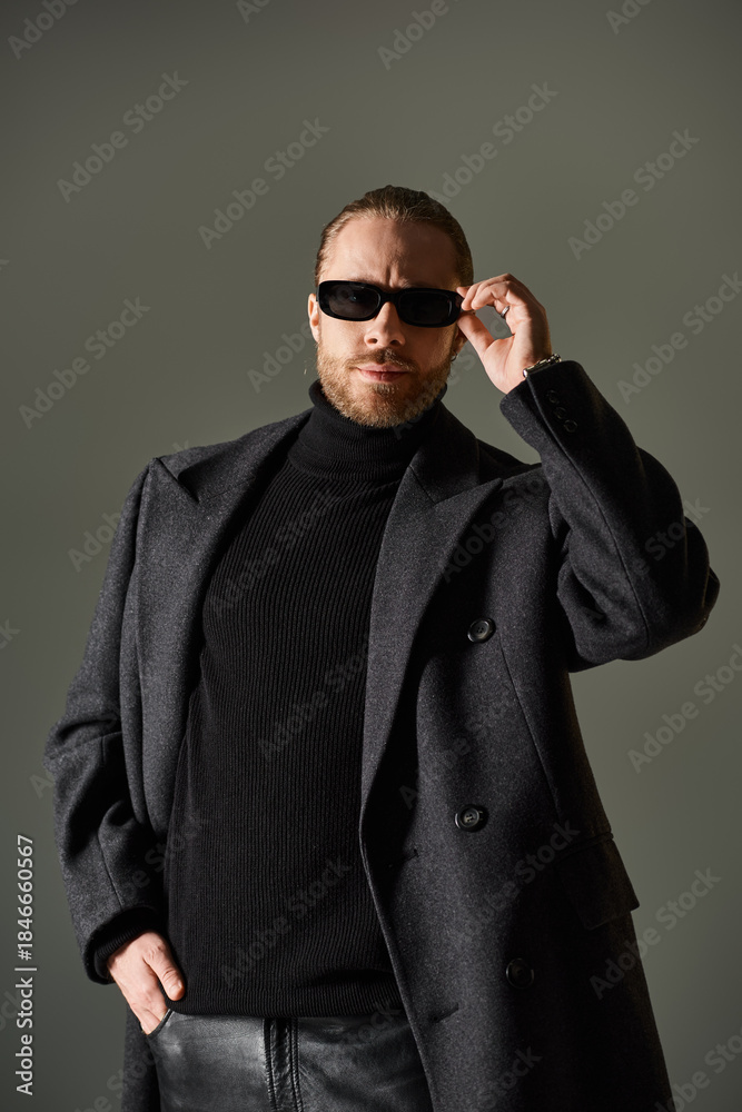 Obraz premium Striking modern style from a handsome man in a chic coat and sunglasses