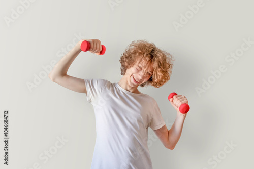 Teen Boy Exercising With Dumbbells At Home In Casual Style. Concept Of Youth Fitness, Gen Z Wellness, Active Lifestyle, Healthy Routines, And Modern Campaigns On Mental And Physical Health