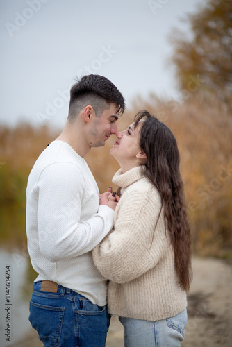A happy young couple is walking on the river bank