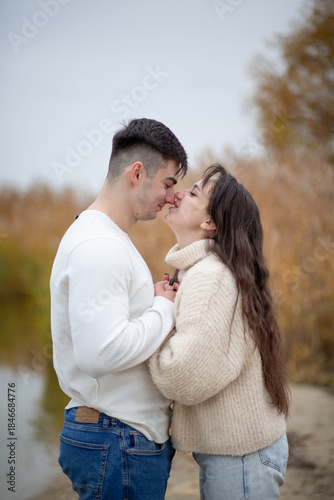 A happy young couple is walking on the river bank