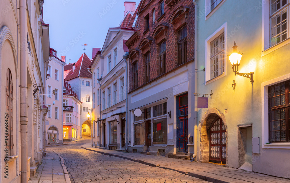 Fototapeta premium Historic cobblestone street with colorful buildings at dawn in Tallinn Old Town, Estonia