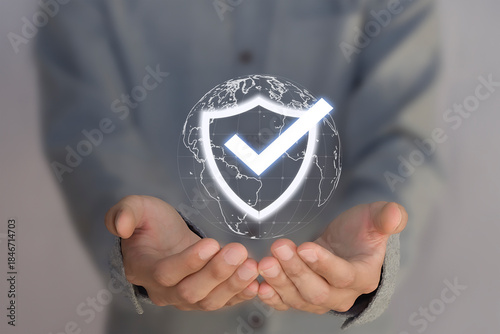 The concept of data protection and security features a businessperson holding a virtual shield with a checkmark icon, representing technology for improving the quality of business services.

