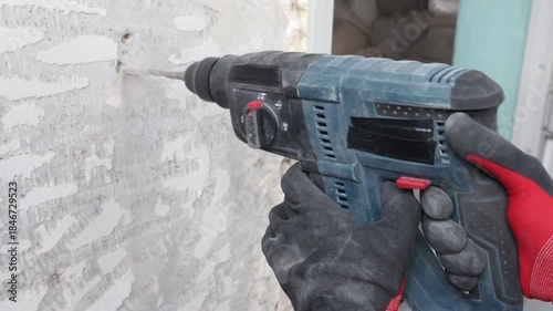 Close-up view of construction worker drilling concrete wall using electric power drill. Renovation and repair process, wall preparation for electrical installation, cable mounting and building interio