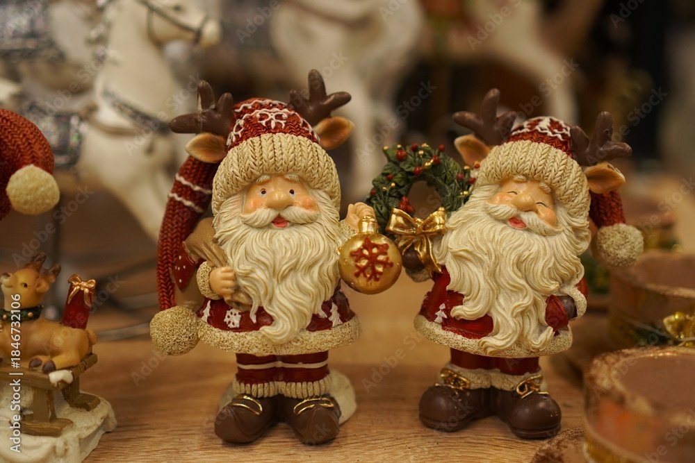 Fototapeta premium lucky vintage Santa Claus figurines in red fur coats with Christmas trees and holiday wreaths on the table close-up as a gift and decoration of winter interiors