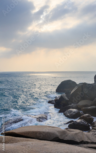 The scenery of Stone Park in Hainan, China, features emerald-green seawater crashing against the rocks, creating beautiful waves.