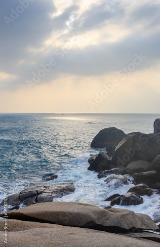 The scenery of Stone Park in Hainan, China, features emerald-green seawater crashing against the rocks, creating beautiful waves.