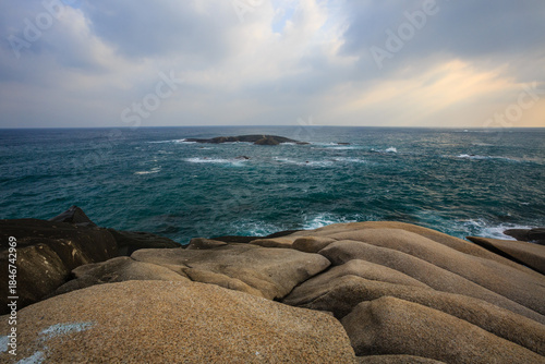 The scenery of Stone Park in Hainan, China, features emerald-green seawater crashing against the rocks, creating beautiful waves.