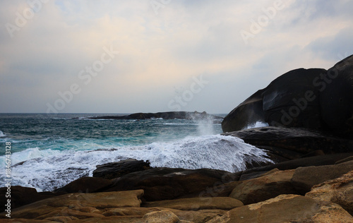 The scenery of Stone Park in Hainan, China, features emerald-green seawater crashing against the rocks, creating beautiful waves.