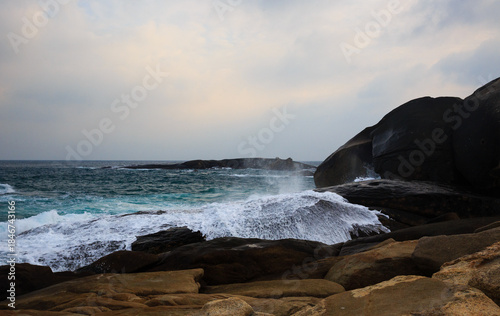 The scenery of Stone Park in Hainan, China, features emerald-green seawater crashing against the rocks, creating beautiful waves.