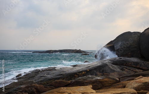 The scenery of Stone Park in Hainan, China, features emerald-green seawater crashing against the rocks, creating beautiful waves.