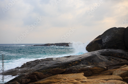 The scenery of Stone Park in Hainan, China, features emerald-green seawater crashing against the rocks, creating beautiful waves.