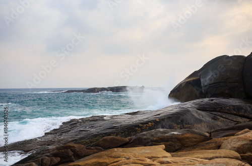The scenery of Stone Park in Hainan, China, features emerald-green seawater crashing against the rocks, creating beautiful waves.