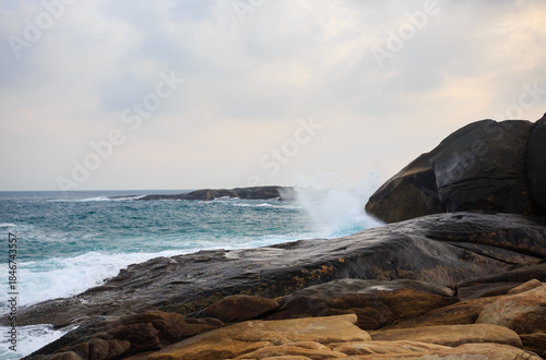 The scenery of Stone Park in Hainan, China, features emerald-green seawater crashing against the rocks, creating beautiful waves.