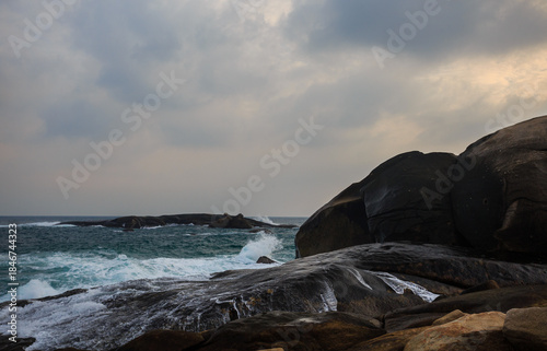 The scenery of Stone Park in Hainan, China, features emerald-green seawater crashing against the rocks, creating beautiful waves.