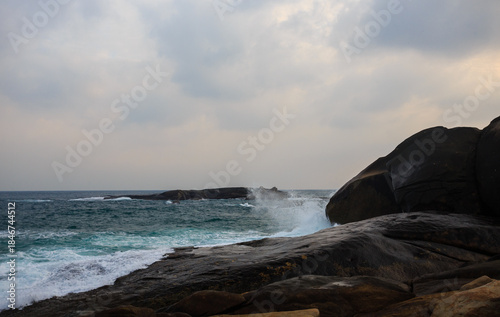 The scenery of Stone Park in Hainan, China, features emerald-green seawater crashing against the rocks, creating beautiful waves.