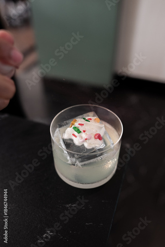 A festive Christmas-themed cocktail in a glass. This drink is perfect for the holidays, featuring an ice decoration in the shape of a tree, perfect to brighten the mood 