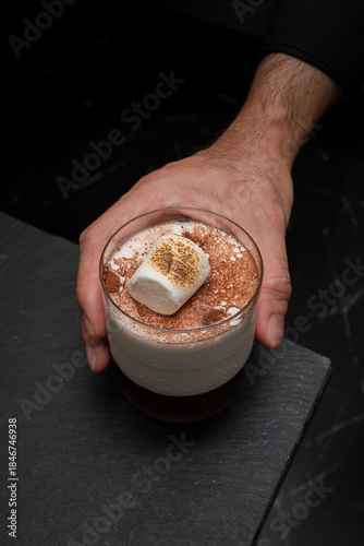 A tempting cocktail in a transparent glass, held by a person's hand, inviting you to taste its delightful flavors