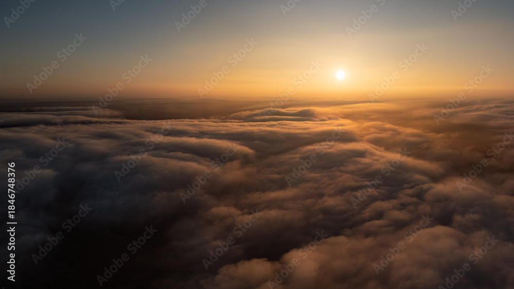 Fototapeta premium Golden sunrise illuminating a vast sea of clouds from above, creating a serene atmosphere