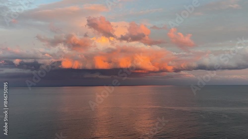 Dramatic sunset clouds glowing in warm golden tones above a calm sea