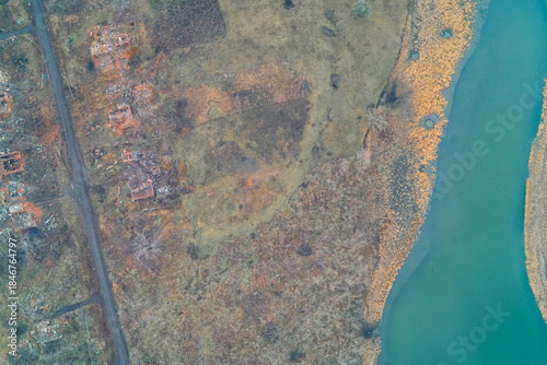Картината върху платно Aerial view of destroyed residential houses on a riverbank showing the contrast