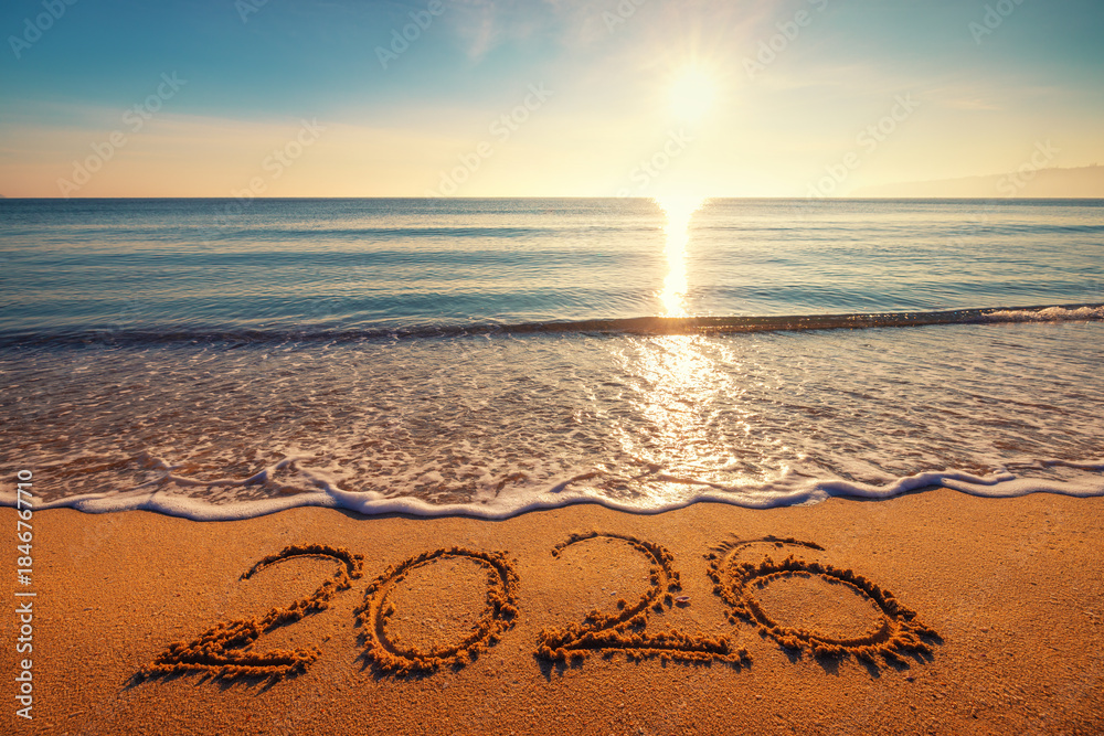 Naklejka premium Golden sunrise over the sea shore and beach and number 2026 happy new year handwritten on the sand