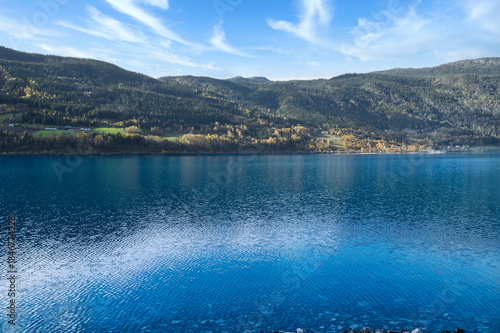 Calm mountain lake with autumnal hills and rocks in the clear water