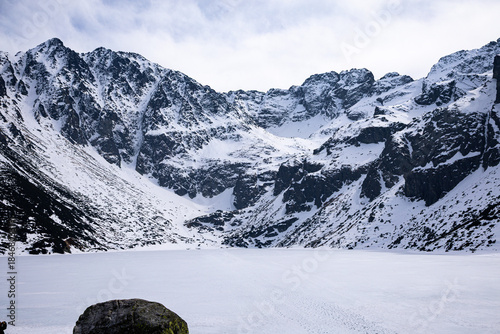 Fototapeta Naklejka Na Ścianę i Meble -  Frozen Black Pond in the Tatra Mountains with rocky peaks of Orla Perć ridge and Kozi Wierch visible in the background