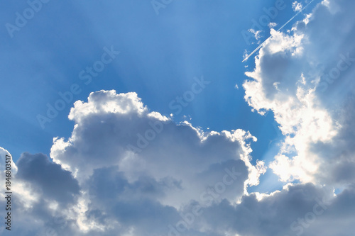 Sunbeams break dramatically through dense clouds in the blue sky.