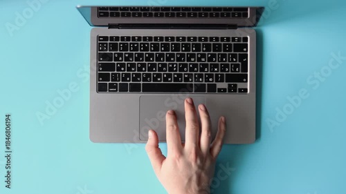 Top view of a person using a laptop on a light blue background.