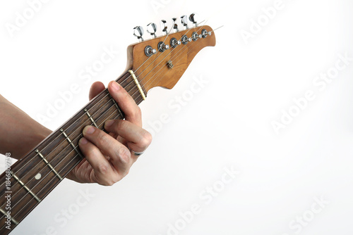 Close-up of a hand of musician playing a guitar neck while forming a chord, showing fingers pressing strings on fret board. Minimal studio shot isolated on white background, capturing guitar technique