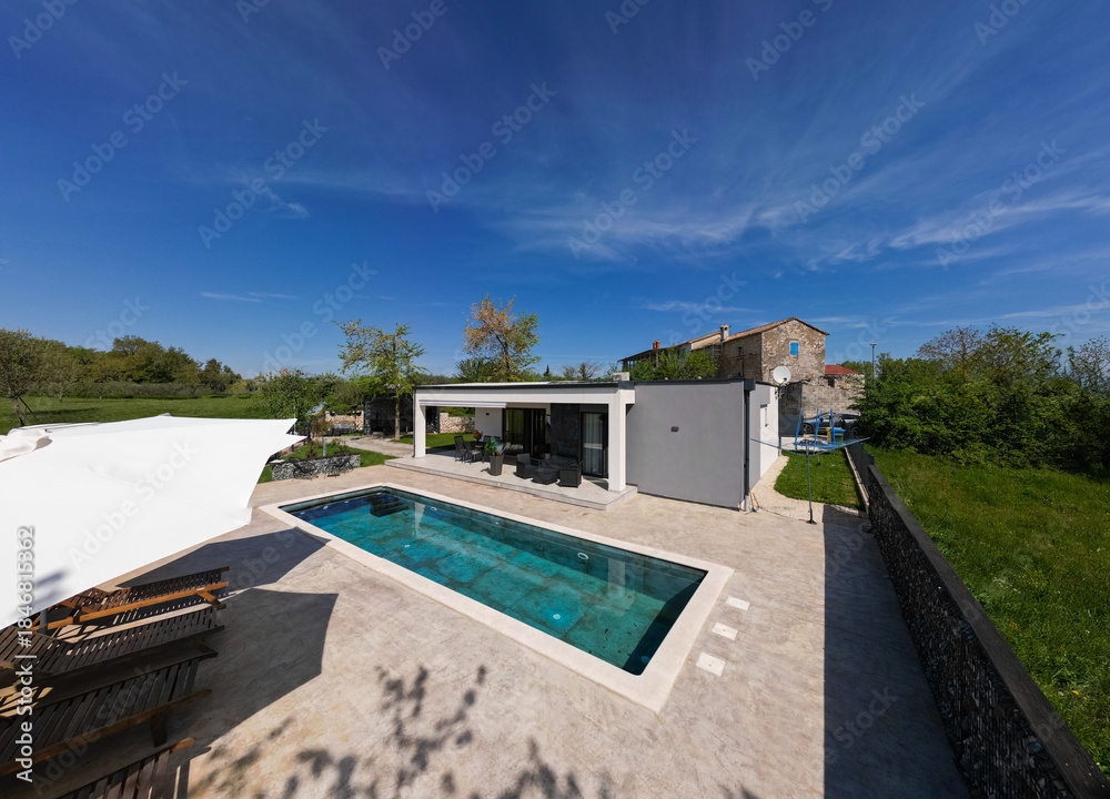 Fototapeta premium Aerial view of a modern modular house with flat roof, swimming pool, and patio. Contemporary prefabricated home architecture featuring sustainable design and outdoor living space