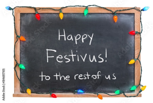 Happy Festivus handwritten in white chalk on a black chalkboard decorated with festive holiday lights isolated on white