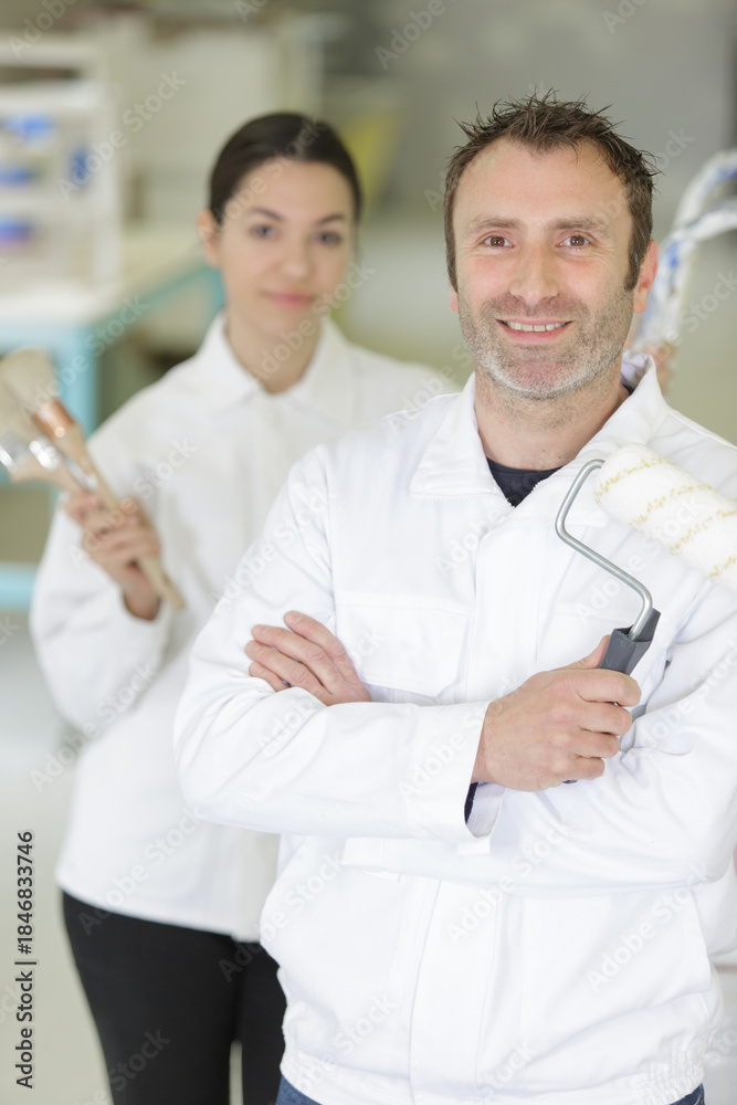 Obraz premium smiling couple with paint brushes