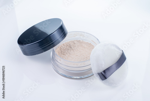 Translucent loose powder with lid and makeup puff isolated on a white background