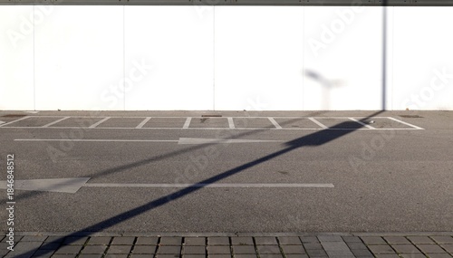 Fotografie Prefab white concrete wall and street in front with motorcycle parking lines and two directional arrows painted