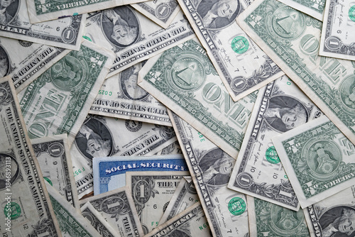 Social security card surrounded by several U.S. one-dollar bills