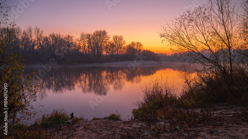 autumn foggy sunrise on the river around forest